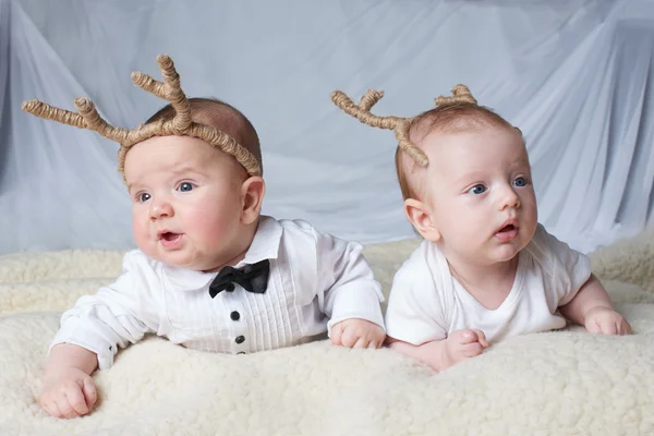 Babies with deer horns on bright background — Stock Photo, Image