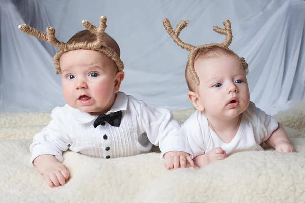 Bebês com chifres de veado em fundo brilhante — Fotografia de Stock