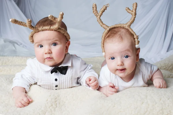 Bebês com chifres de veado em fundo brilhante — Fotografia de Stock