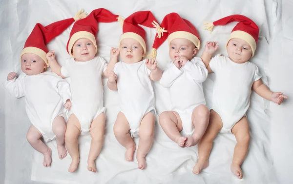 Bebês com chapéus de Papai Noel em fundo brilhante — Fotografia de Stock