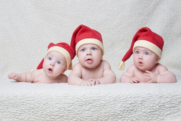 Bebês com chapéus de Papai Noel em fundo brilhante — Fotografia de Stock