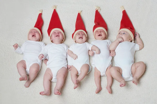 Babys mit Weihnachtsmützen auf hellem Hintergrund — Stockfoto