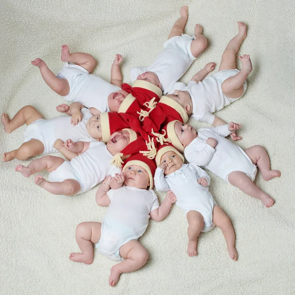 Bebês com chapéus de Papai Noel em fundo brilhante — Fotografia de Stock