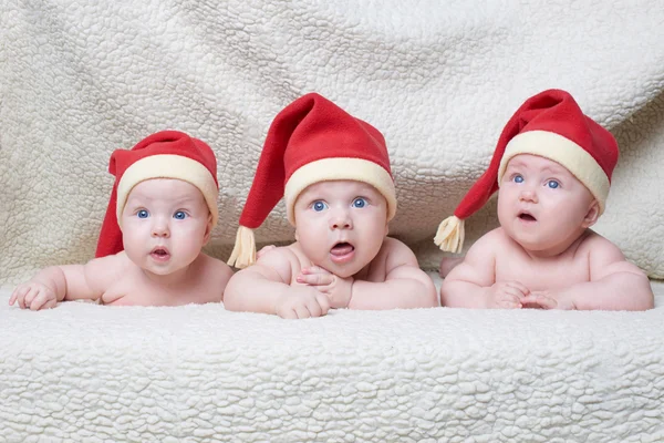 Babies with santa hats on bright background — Stock Photo, Image