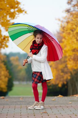 Kız sonbahar Park gökkuşağı şemsiyesi altında