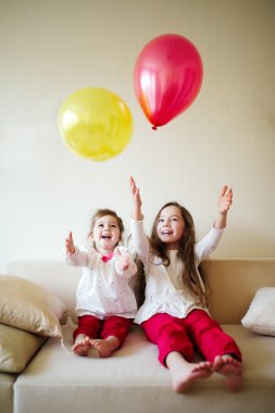 evde balonlarla oynayan kızlar