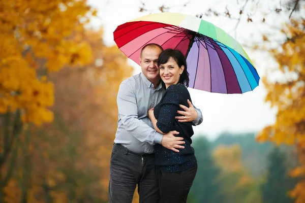 Чоловік і жінка під яскравою кольоровою парасолькою — стокове фото