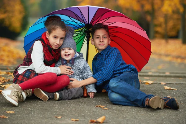 Happy children under rainbow umbrella — Stock Photo, Image