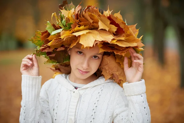 Hermosa chica en el parque de otoño con corona de hojas — Foto de Stock