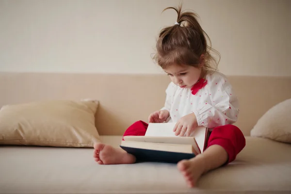 Liten flicka läser bok hemma — Stockfoto