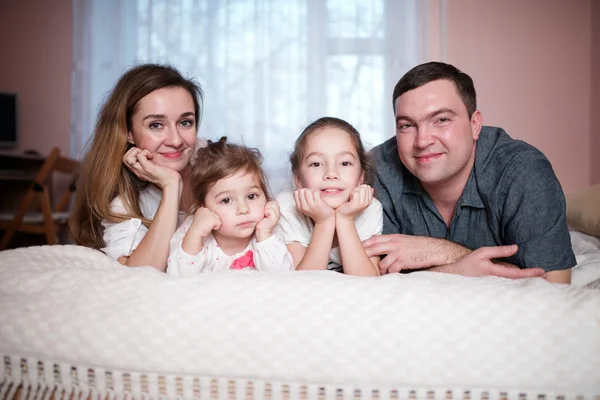 Feliz joven familia acostada en la cama — Foto de Stock