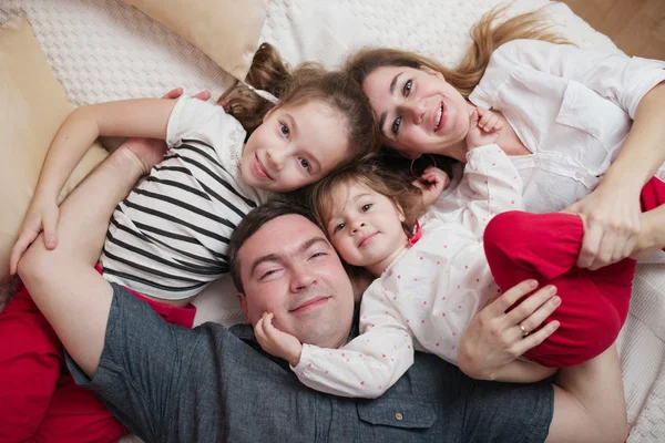 Ευτυχής νεαρή οικογένεια ξαπλωμένη στο κρεβάτι — Φωτογραφία Αρχείου