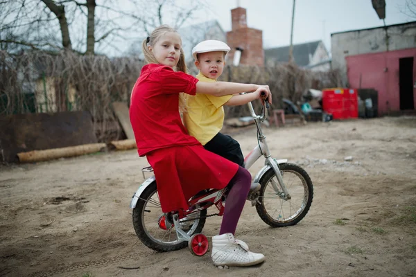 Children ride on bicycle in yard — Stock Photo, Image