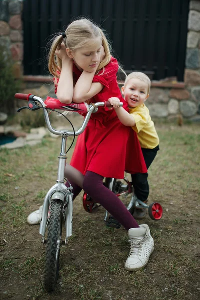 Children ride on bicycle in yard — Stock Photo, Image