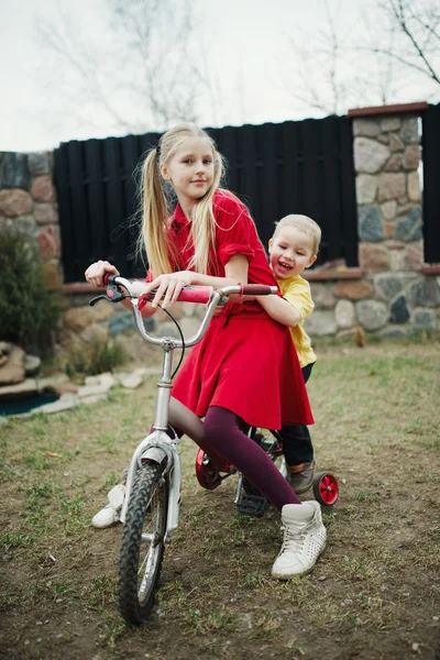 Children ride on bicycle in yard — Stock Photo, Image