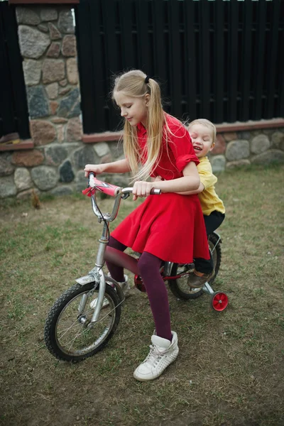 Children ride on bicycle in yard — Stock Photo, Image