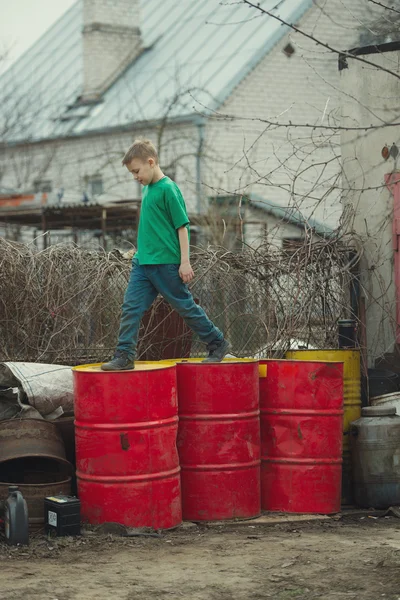 Boy walks on the barrels from oil — Stock Photo, Image