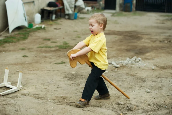 Мальчик играет с деревянной лошадью — стоковое фото