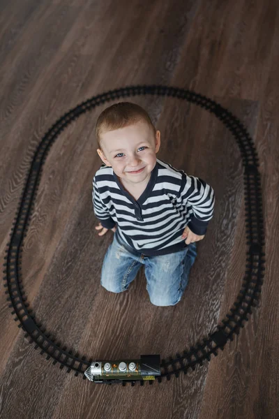 Маленький хлопчик будує іграшкову залізницю — стокове фото