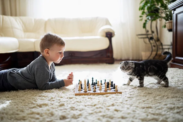 Niño juega al ajedrez tirado en el suelo —  Fotos de Stock