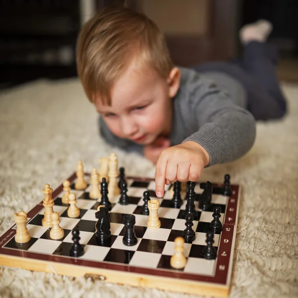 Petit garçon joue aux échecs couché sur le sol — Photo