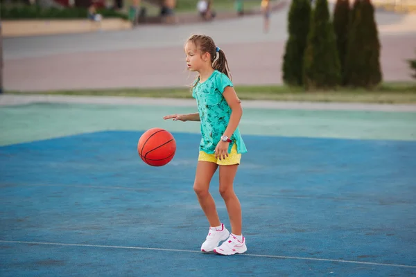 Pequeña linda chica jugando baloncesto al aire libre Imagen de archivo