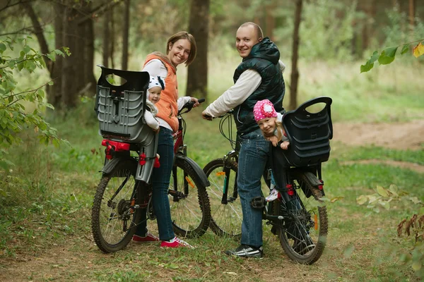 Счастливая семья ездит на велосипеде в лесу — стоковое фото