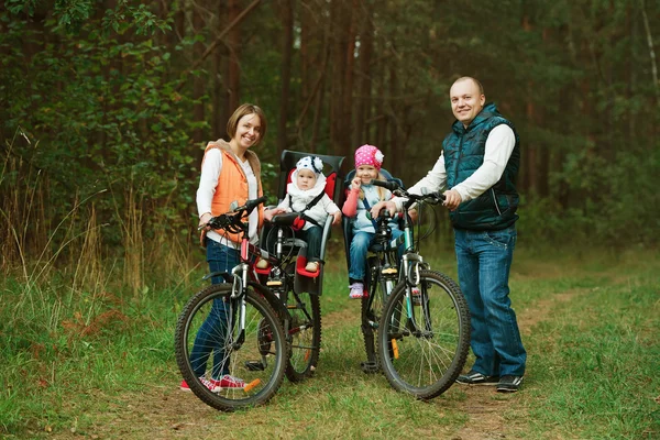 Счастливая семья ездит на велосипеде в лесу — стоковое фото