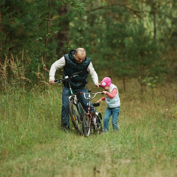Батько і дочка катаються на велосипеді в лісі — стокове фото