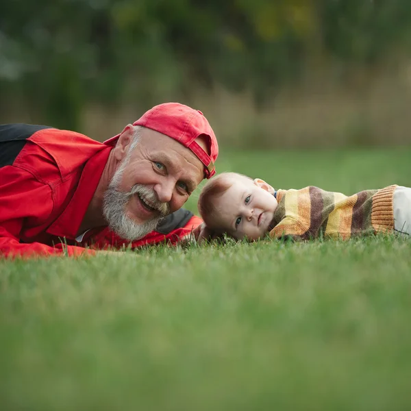 Grandfather and grandson lying on grass — Stock Photo, Image