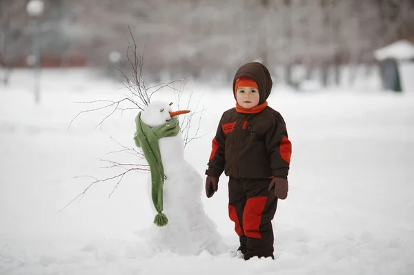Ragazzino con pupazzo di neve — Foto Stock