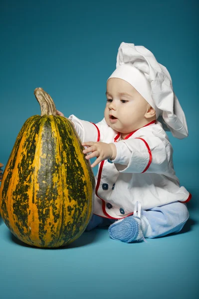 Divertido bebé con traje de cocinero sostiene la calabaza —  Fotos de Stock