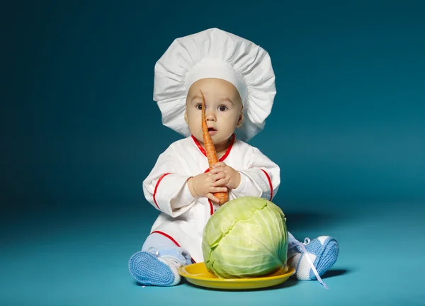 Смішна дитина з кулінарним костюмом тримає моркву — стокове фото