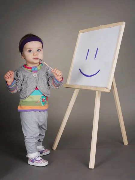 Girl draws with brush on easel — Stock Photo, Image