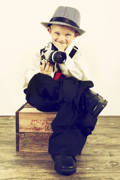 Jongen speelt met een oude camera als fotograaf — Stockfoto