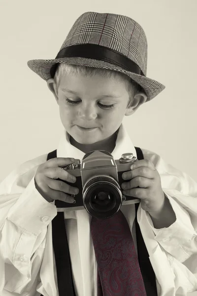 Jongen speelt met een oude camera als fotograaf — Stockfoto