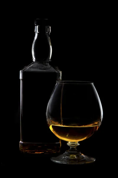 Cognac glass and bottle with brandy with rim lighting