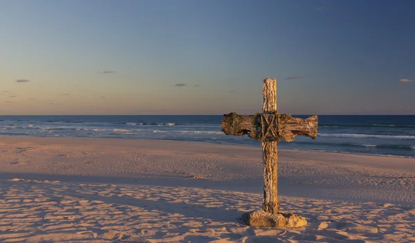 Una vieja cruz sobre una duna de arena junto al océano con un tranquilo amanecer —  Fotos de Stock