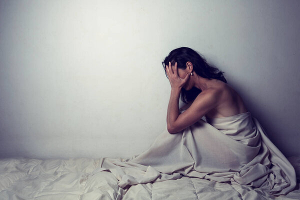 Conceptual image of a woman a sad and lone on a bed under a sheet