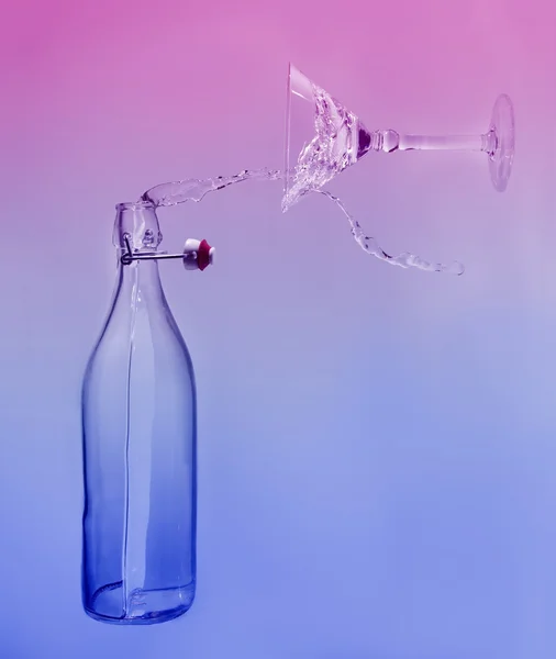 De l'eau claire verser horizontalement hors de la bouteille éclabousser dans le verre avec — Photo