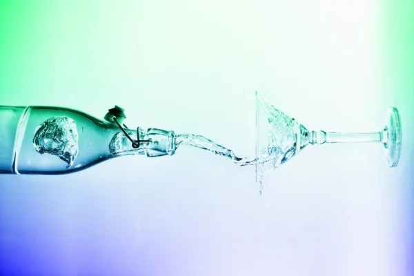 Clear water pour horizontal out of bottle splash into glass with — Stock Photo, Image