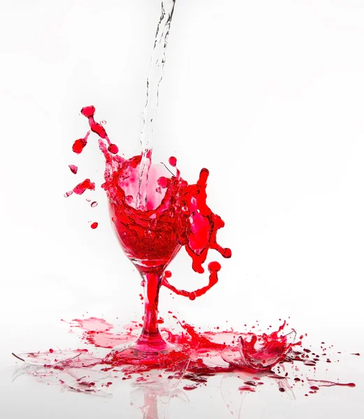 Red water spill from a broken wine glass on a white background — Stock Photo, Image