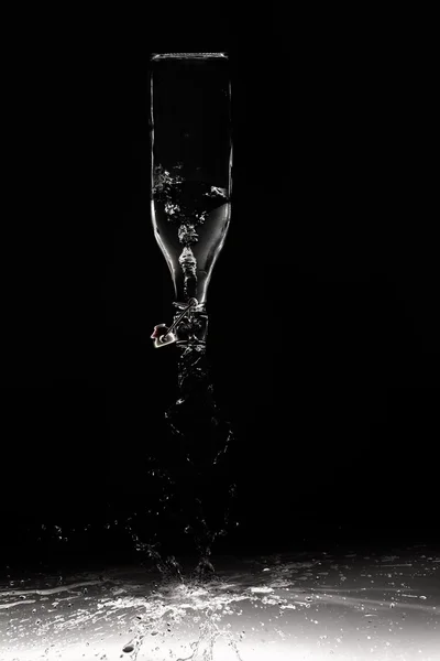 Helder water lekkage uit een glazen fles op zwarte achtergrond op shi — Stockfoto