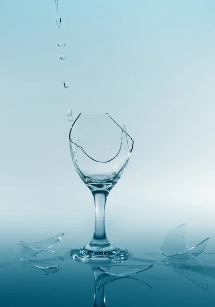 Clear water pour out of bottle splash into glass and spill with