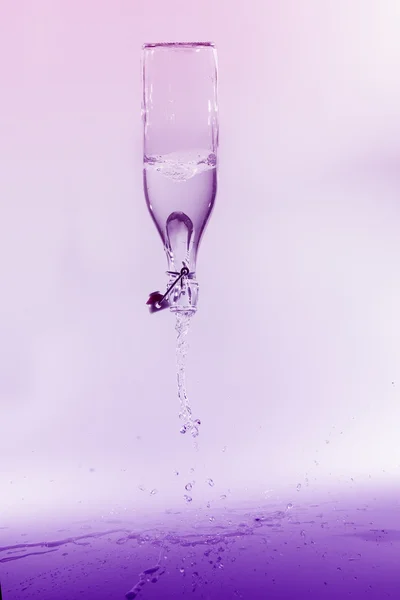 Déversement d'eau claire à partir d'une bouteille en verre sur fond violet sur sh — Photo