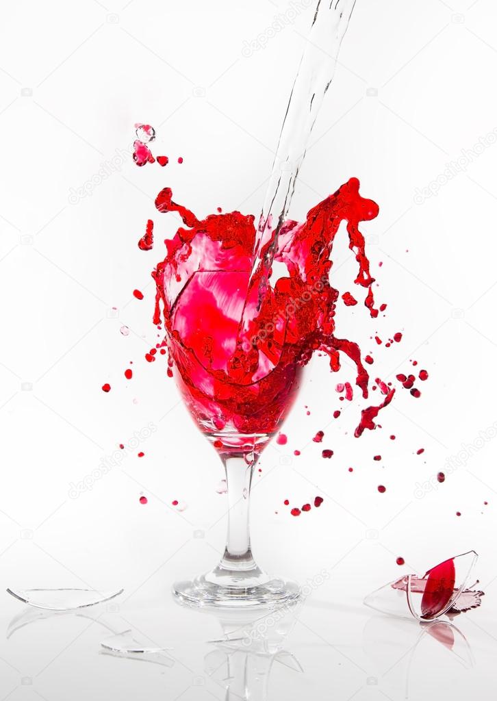 Red water spill from a broken wine glass on a white background