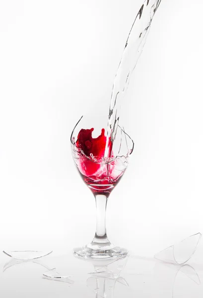 Derrame de agua roja de una copa de vino rota sobre un fondo blanco — Foto de Stock