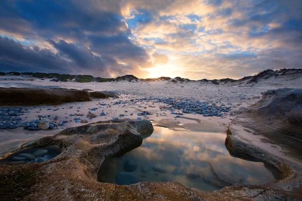 Spiaggia di paesaggio a tarda sera sulla riva rocciosa e tramonto incandescente — Foto Stock