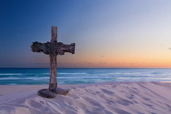 An old cross on sand dune next to the ocean with a calm sunrise — Stock Photo, Image