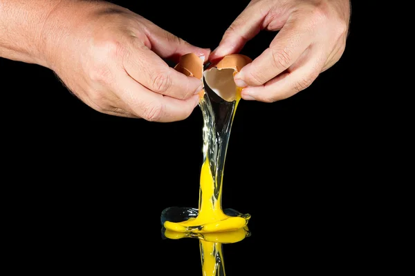 Duas mãos quebrar ovo no fundo preto — Fotografia de Stock